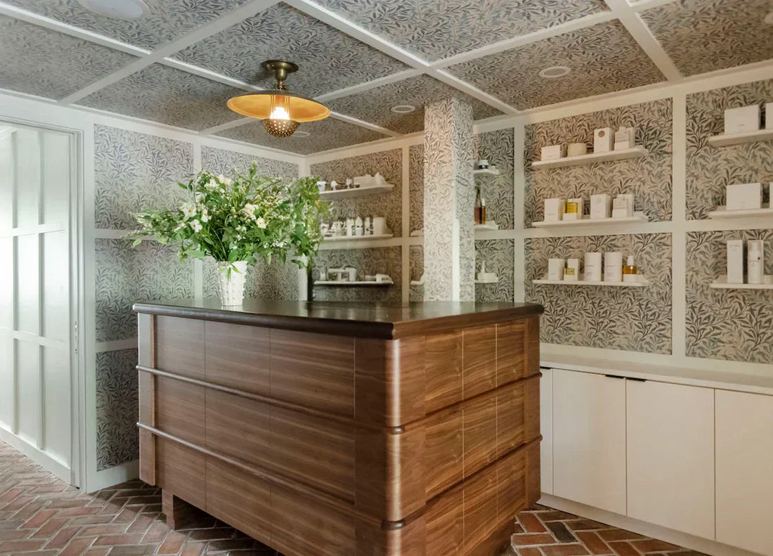 Modern Sommetbeauty spa reception with wooden desk, patterned walls, and skincare products displayed on shelves.