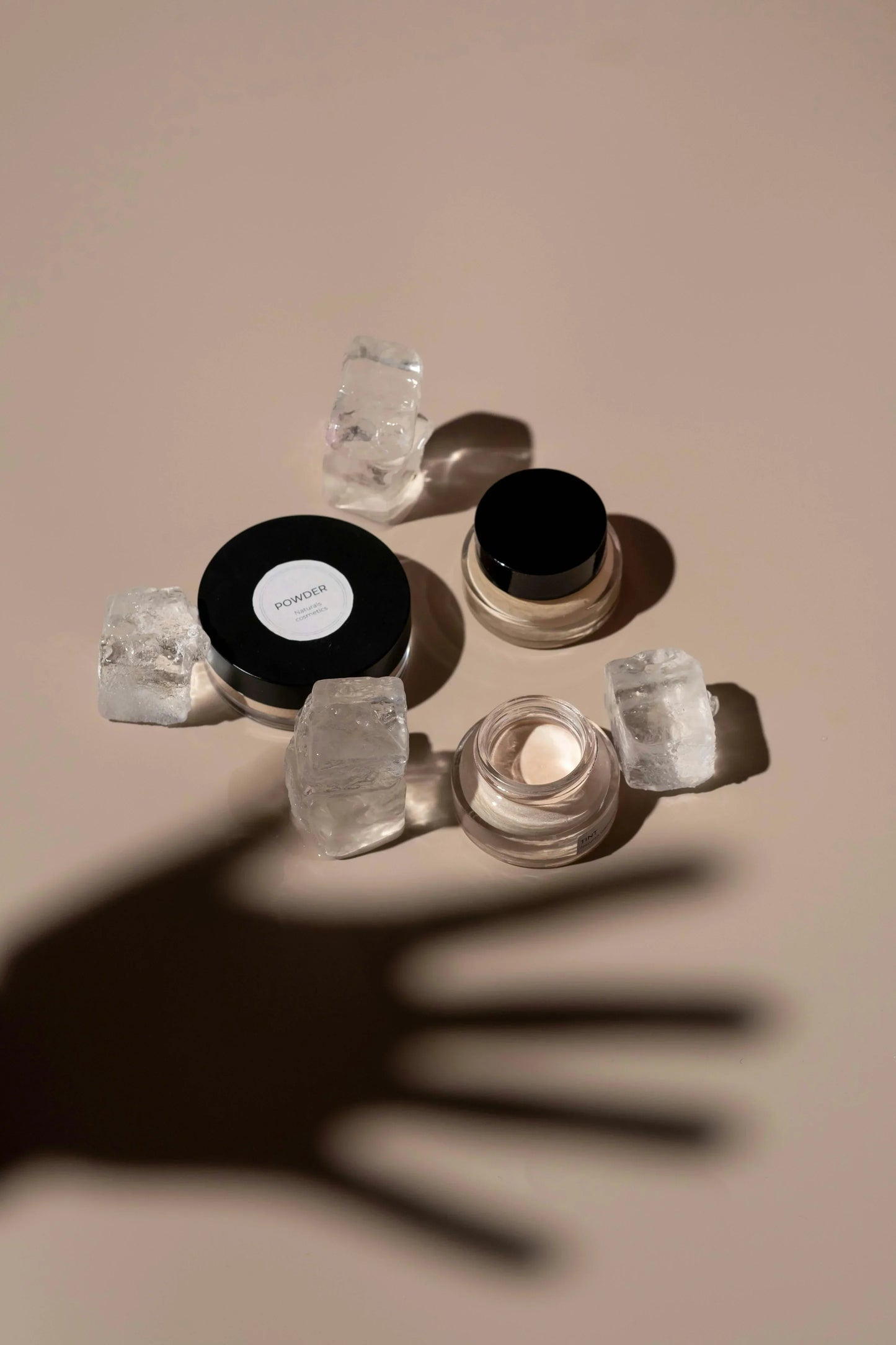 Sommetbeauty skincare powders and creams styled with ice cubes on a beige background.