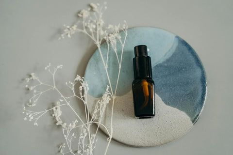 Sommetbeauty body spray bottle styled on a ceramic plate with dried, white florals.
