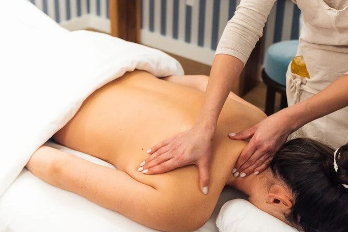 Massage therapist giving a back massage to a client in a spa setting.